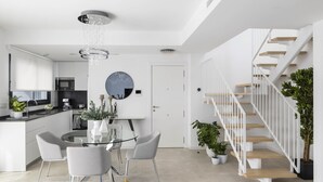 Une cuisine moderne avec un coin repas, un escalier et des plantes en pot.