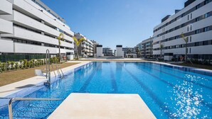Un hôtel moderne doté d’une piscine centrale, de nombreux balcons et offrant une vue sur un ciel d’un bleu éclatant.