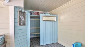 A room with a blue door, a sign reading "SEASIDE," and a wicker chair.
