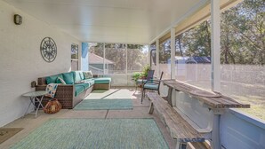 A covered patio with a wicker sofa, a wooden table, and a bench. - 1 Mi to Golf: Citrus Springs Retreat w/ Fire Pit! (Citrus Springs)