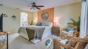 A bedroom with a bed, nightstands, wicker chairs, a ceiling fan, and a wall-mounted artwork. - 1 Mi to Golf: Citrus Springs Retreat w/ Fire Pit! (Citrus Springs)