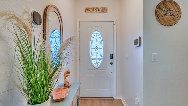 A hallway with a white door, a wooden sign above it, a wall-mounted thermostat, and a decorative plate with the words "Simply Blessed". - 1 Mi to Golf: Citrus Springs Retreat w/ Fire Pit! (Citrus Springs)