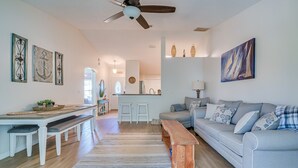 A spacious living room with a light blue sofa, a wooden bench, and a dining area with a white table and benches. - 1 Mi to Golf: Citrus Springs Retreat w/ Fire Pit! (Citrus Springs)
