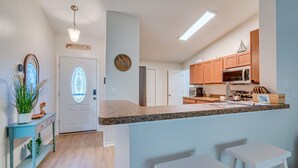 A modern kitchen with granite countertops, wooden cabinets, and a central island with bar stools. - 1 Mi to Golf: Citrus Springs Retreat w/ Fire Pit! (Citrus Springs)