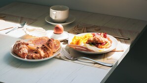 A breakfast table with plates of food and a view of a beach through a window. - Hotel Centrale Miramare (Rimini)