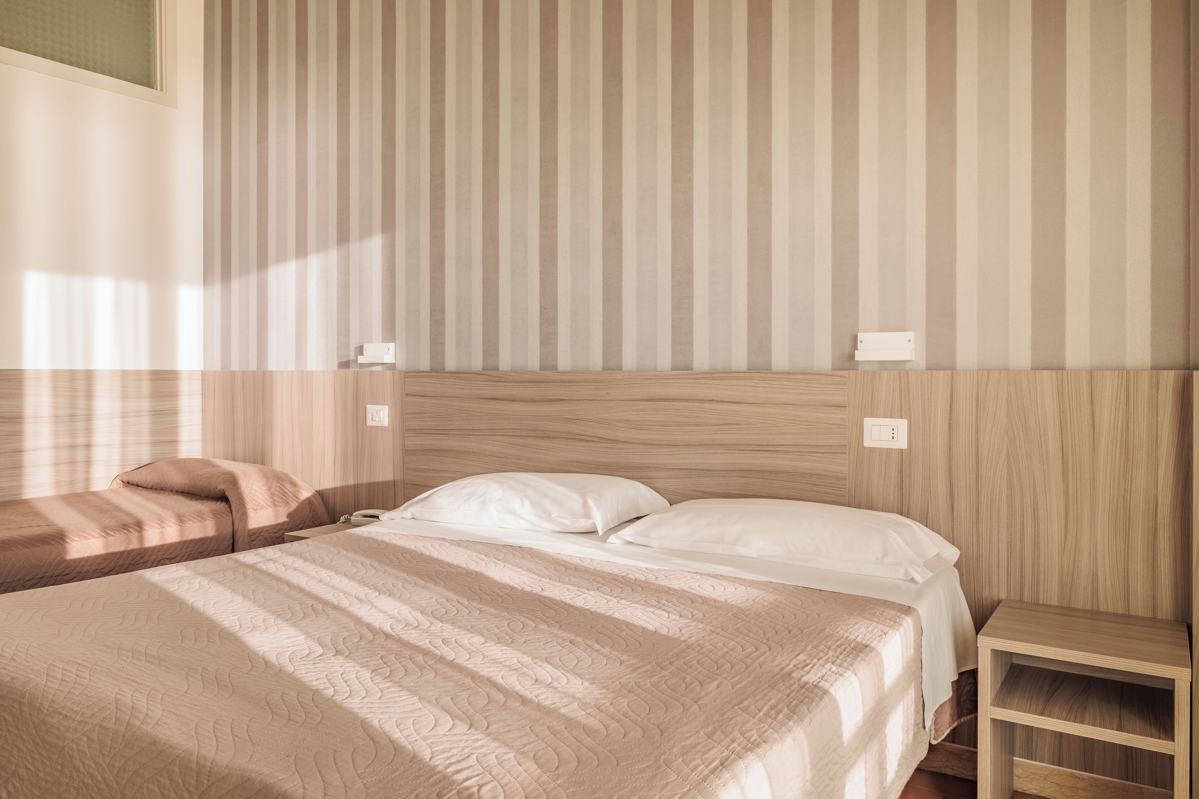 A hotel room with a large bed, a smaller bed, and a nightstand.