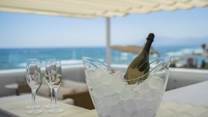 A champagne bottle in an ice-filled bucket on a table with two empty glasses, overlooking a beach. - Villa Dune Costabella (Marbella)
