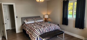 A bedroom with a bed, bedside table, lamp, and a window with curtains. - Waterfront, AC, Newly Remodeled, Kayaks, 4 SUP, Rowboats (Frankfort)