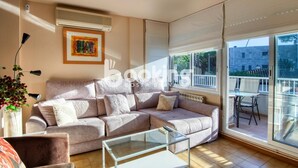 Ein Wohnzimmer mit einem beigefarbenen Sofa, einem Glastisch und einem großen Fenster mit Ausblick.