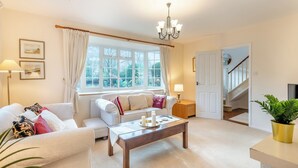 A living room with a sofa, coffee table, and a staircase leading to another room. - The perfect larger family sized home with vast, lush, enclosed garden. (Trunch)