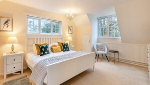 A bedroom with a white bed, multiple windows, a chair, and a radiator. - The perfect larger family sized home with vast, lush, enclosed garden. (Trunch)
