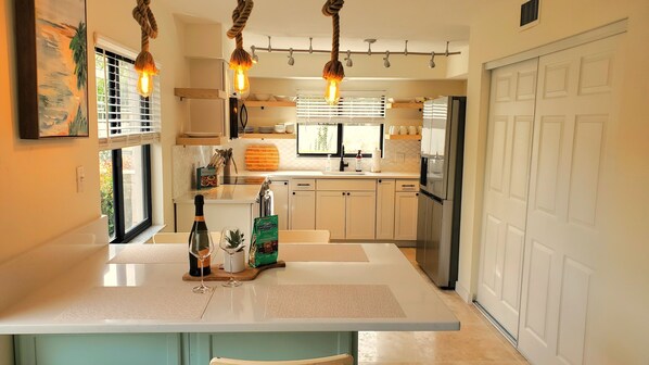 Una cocina moderna con una isla central, electrodomésticos de acero inoxidable y vistas al exterior.
