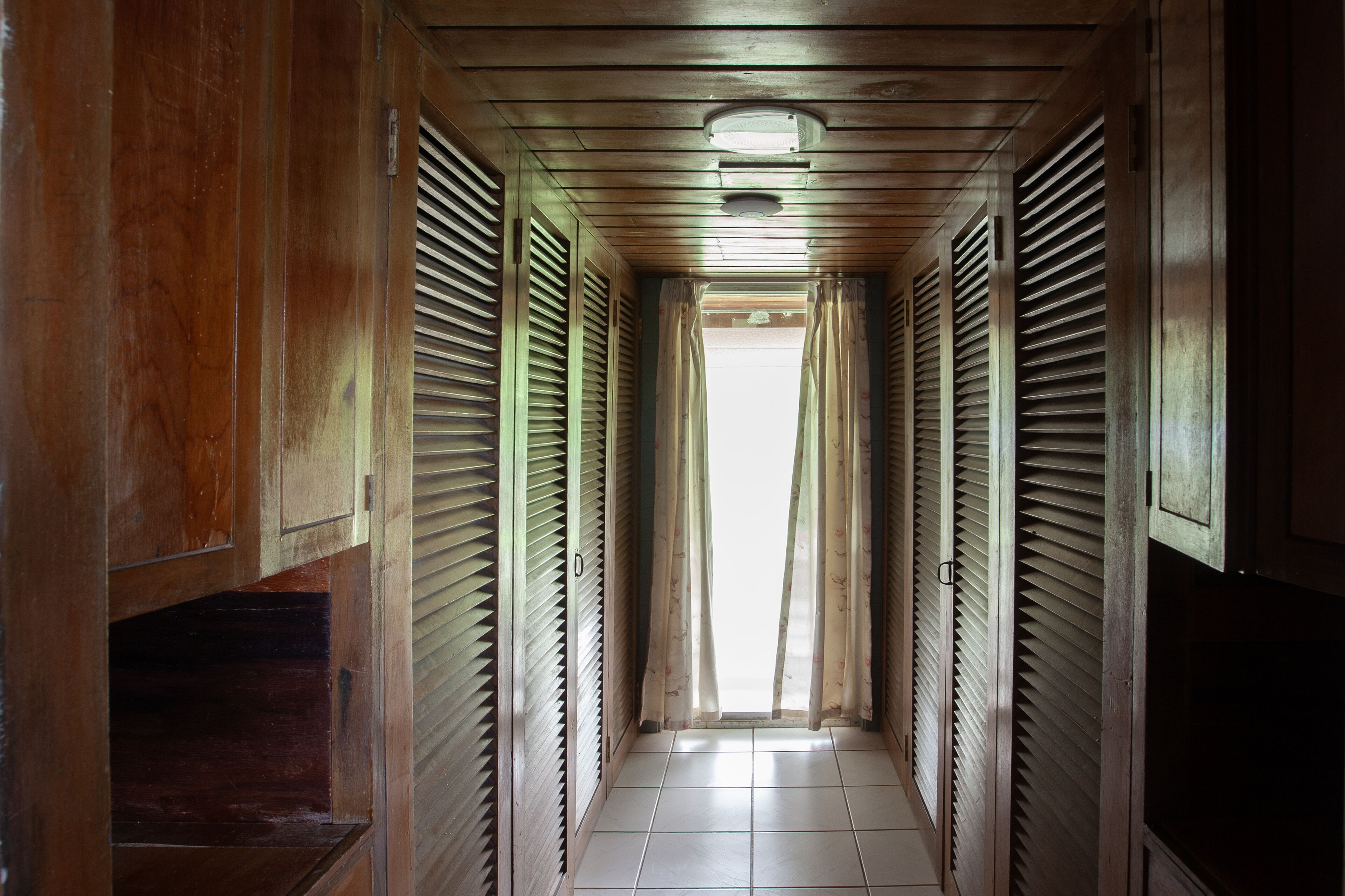 A narrow hallway with wooden paneling and a tiled floor.
