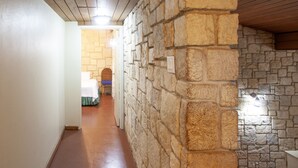 A hallway with stone walls, a wooden ceiling, and a tiled floor. - Two Bedroom Garden View Villa, Frenchman's Cove Resort (Drapers)