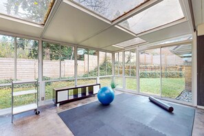 A spacious room with large windows, a blue exercise ball, and a yoga mat.