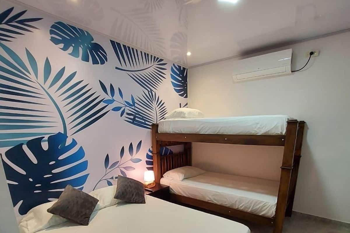 A room with a bunk bed and a single bed, both with white bedding.