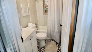 A bathroom with a toilet, bathtub, and a shower curtain. - Cincinnati Themed, Historic Big Sky Apartments! (Cincinnati)