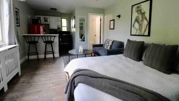 A cozy room with a bed, a sofa, and a small kitchen area. - Cincinnati Themed, Historic Big Sky Apartments! (Cincinnati)