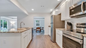 A modern kitchen with stainless steel appliances, wooden countertops, and a view to the dining area. - Hidden Gem in Pooler (Pooler)