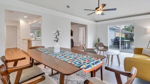 A dining area with a long table, chairs, a ceiling fan, and a view of the outdoors. - Hidden Gem in Pooler (Pooler)