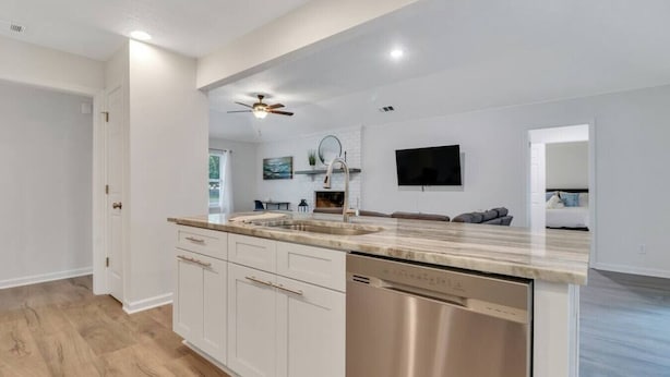 A modern kitchen with white cabinetry, a stainless steel dishwasher, and a granite countertop. - Hidden Gem in Pooler (Pooler)