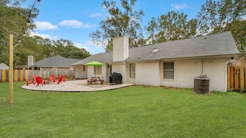 A single-story house with a backyard patio, a barbecue grill, and a water tank.