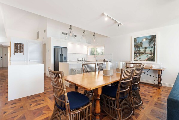 A modern kitchen with white cabinets, a dining table with chairs, and a large window.
