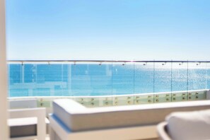 A balcony with a view of the sea and a white outdoor seating area.