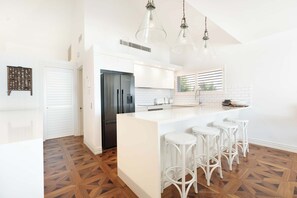 Uma cozinha moderna com uma ilha central, banquetas e iluminação pendente.