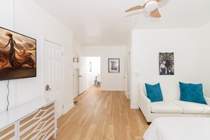 A modern, well-lit room with a white sofa, a ceiling fan, and artwork on the walls. - 545 Michigan Avenue Apartments (Miami Beach)