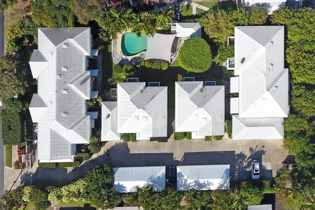 An aerial view of a residential area with multiple houses, a swimming pool, and a covered outdoor area.