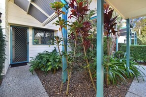 A house with a covered porch, a gated entrance, and various plants.