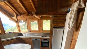 Una cocina rústica con armarios de madera, una encimera blanca, un lavamanos, un lavavajillas, un horno y un refrigerador.