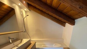 Un baño moderno con un tocador de madera, una bañera y una ducha.