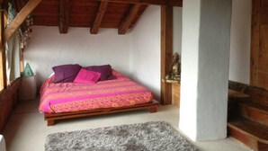 Un dormitorio con una cama de madera, una mesita de noche pequeña y una estatua de Buda.