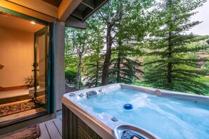 Un jacuzzi en un balcón con vistas a árboles y casas.