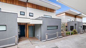 A modern building with a flat roof, large windows, and a gated entrance. - Oceania 8 (Lorne)