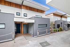 A modern building with a flat roof, large windows, and a gated entrance. - Oceania 8 (Lorne)