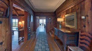 A wooden hallway with a rug, a bench, and a table with a lamp. - Large Historic Home with views of Crystal Lake & Lake Michigan (Frankfort)