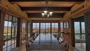 A large wooden dining table with chairs, large windows, and a chandelier. - Large Historic Home with views of Crystal Lake & Lake Michigan (Frankfort)
