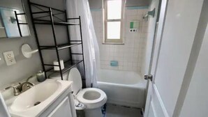 Een kleine badkamer met toilet, wastafel en douchehoek.