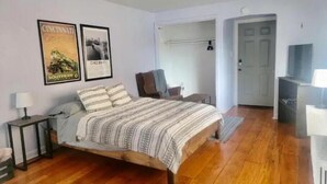 Een slaapkamer met een houten bed, nachtkastje, stoel en een tv-meubel.