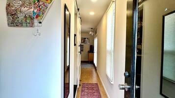 A hallway with a purple carpet, a bulletin board with comics, and a door with a glass panel.