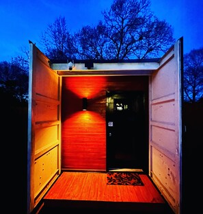 Een klein, afgesloten gebouwtje met een houten vloer en een rode binnenkant, mogelijk een tuinhuisje of een kleine opslagruimte.