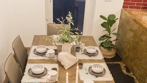 A dining table set with plates, bowls, and cups, surrounded by chairs.