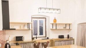 A kitchen with a wooden countertop, a microwave, a toaster, and a hanging light fixture.