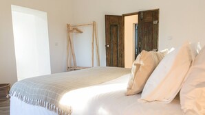 A bedroom with a large bed, a wooden door, and a wooden hanger on the wall.