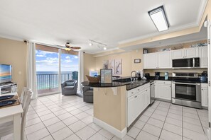 A modern kitchen with white cabinets, a built-in microwave, and a large island.