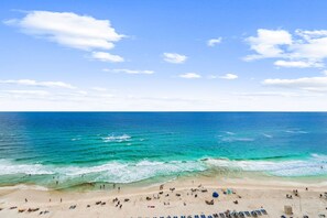 Ein Strand mit blauem Himmel, Wellen und Menschen.