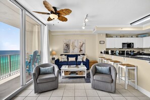 Un salon moderne comprenant un canapé, deux fauteuils, une table basse et un balcon avec vue.